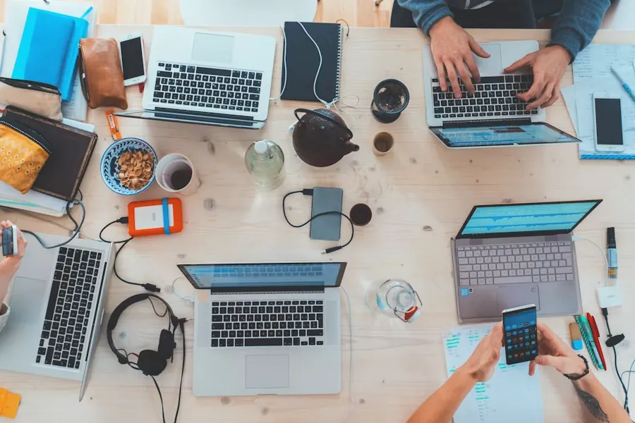 People collaborating on laptops and phones around a shared desk